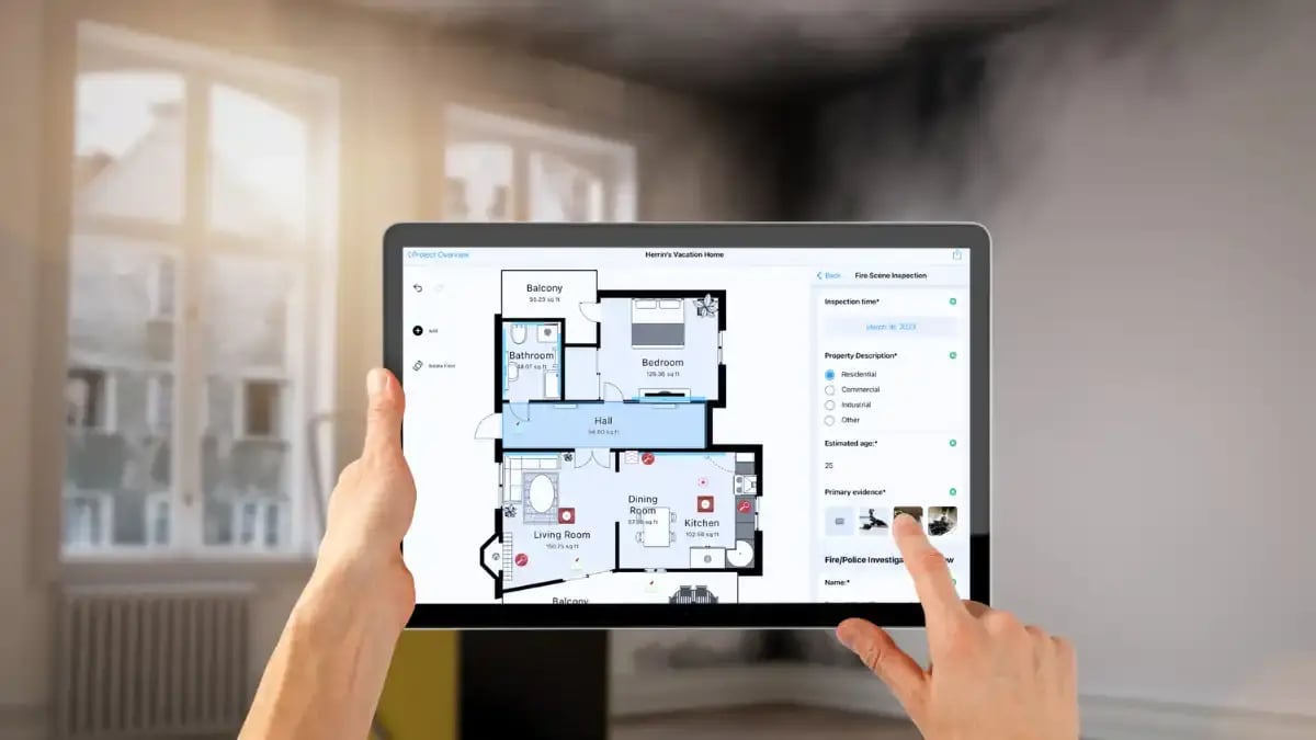 A contractor using a tablet to document a fire-damage scene