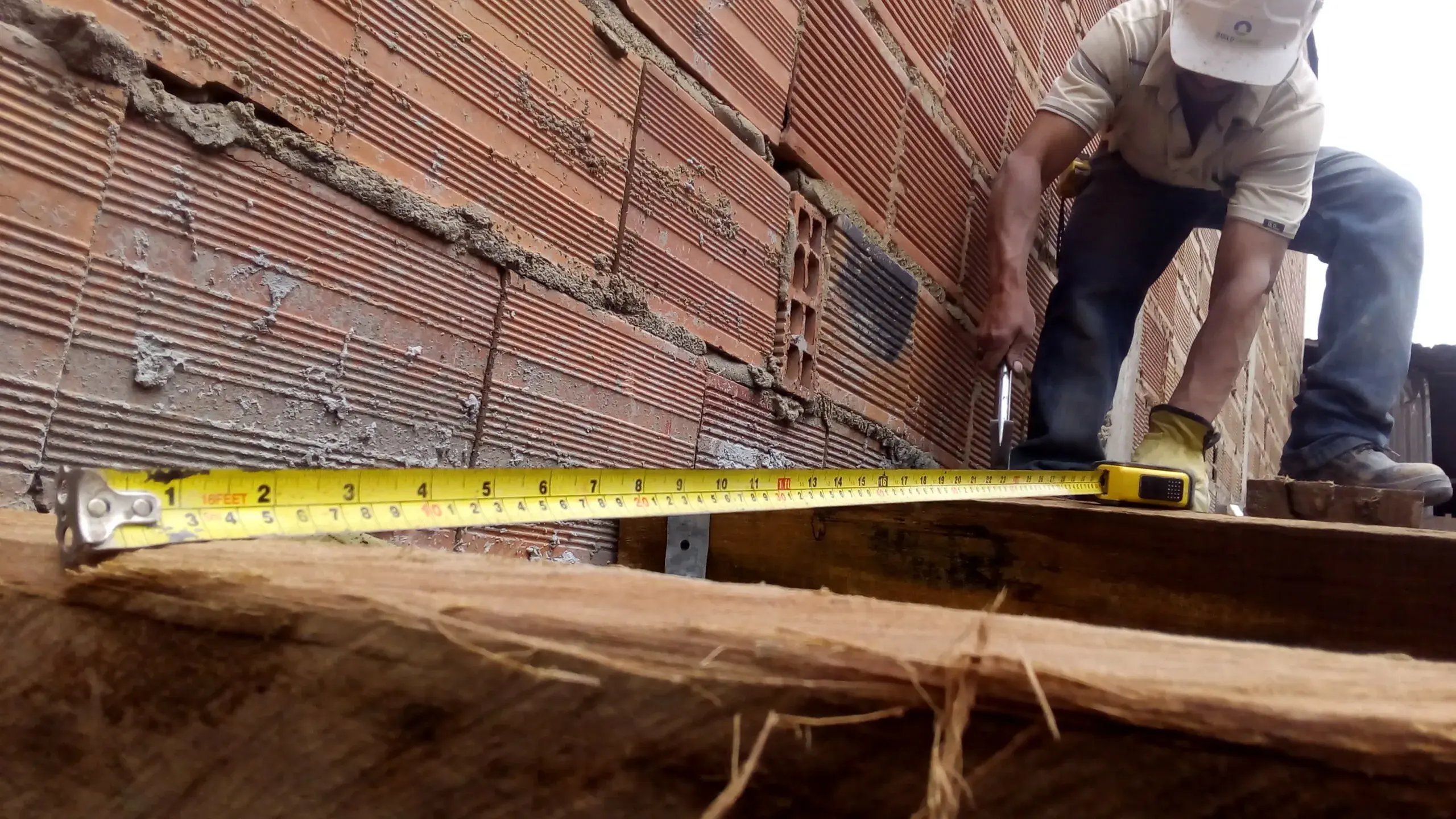 Builder from Buildchange measuring a construction building site with a tape measurer.