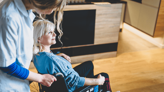 nurse daughter carries wheelchair-bound elderly woman through her newly remodeled kitchen