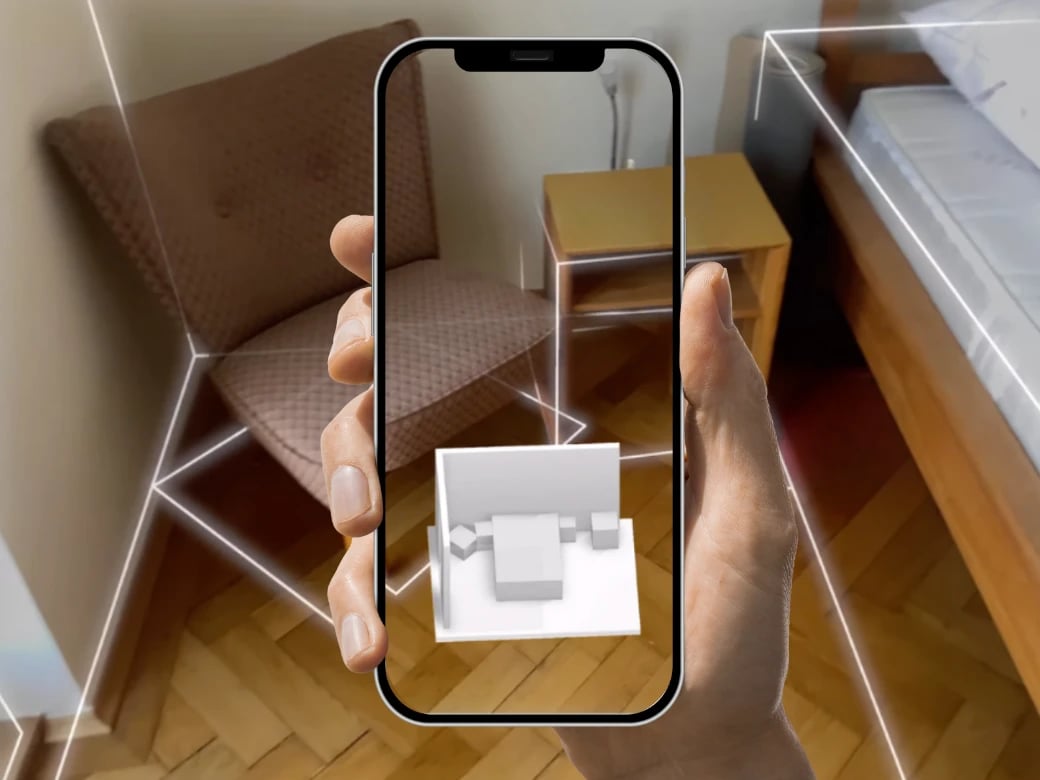 Scanning a room with magicplan Auto-Scan feature with LiDAR on a bedroom with a chair, bed, and table using and iphone beign hold by the hand of a contractor