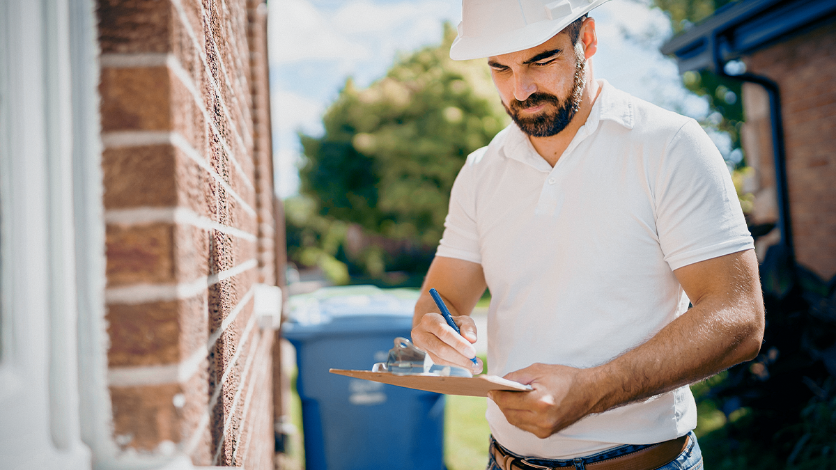 A man wearing a hard hat writing on a note pad